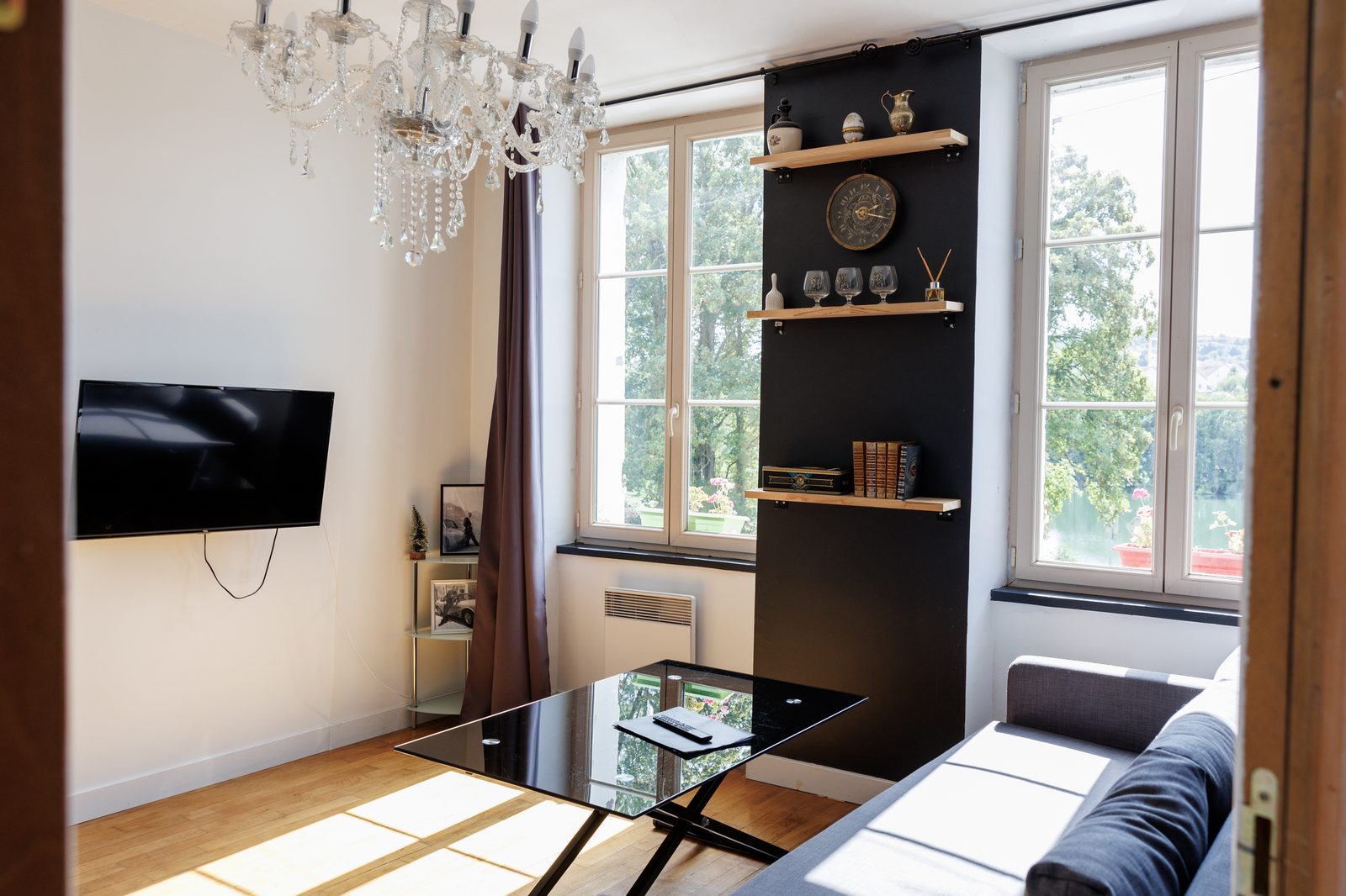 Salon de l'appartement L'Aston avec vue sur l'Yonne, canapé et lustre en cristal - Pont-sur-Yonne