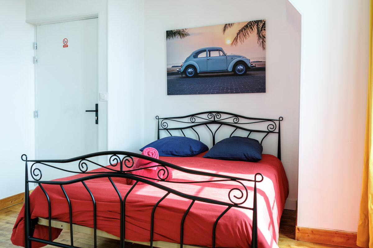 Chambre du Cox, lit double fer forgé, linge rouge, tableau Volkswagen Coccinelle — KM99 Pont-sur-Yonne