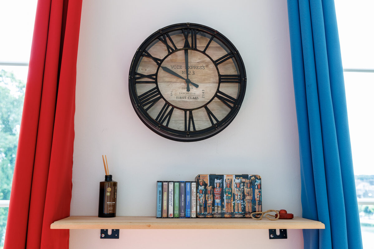 Détail décoration Le Cox, grande horloge Voie Express, rideaux colorés rouge et bleu — KM99