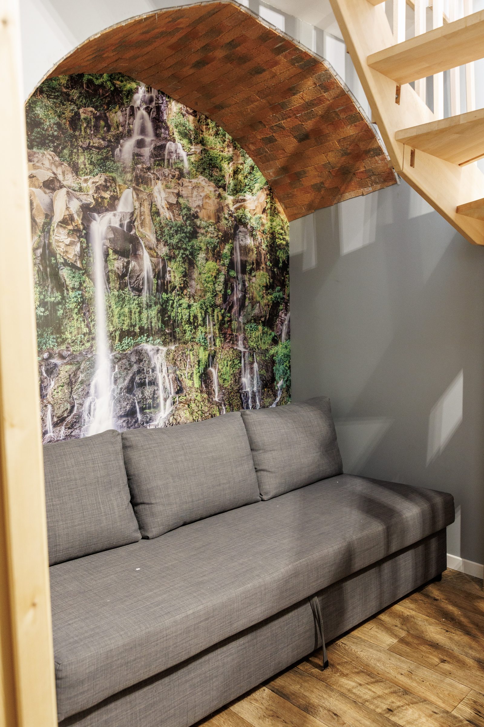 Canapé-lit sous arche en brique avec fresque cascade — Le Sésame