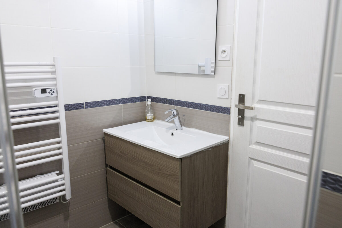 Salle de bain La Vitrine, meuble vasque bois, sèche-serviettes et carrelage gris — La Graineterie